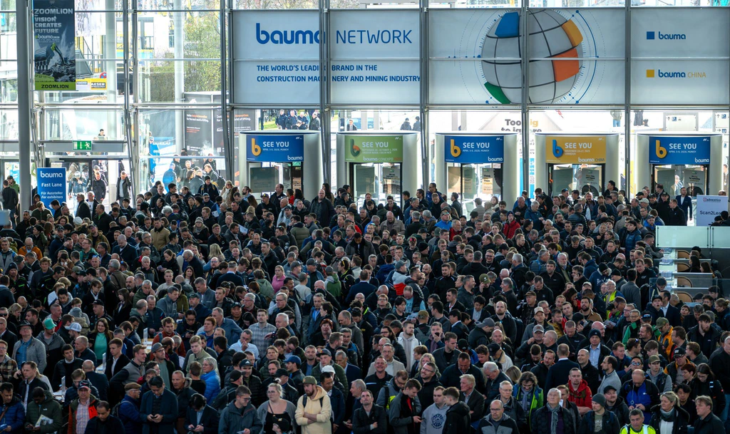 Besucherinnen und Besucher warten am Eingang der Bauma. Vor allem die Zahl der Gäste aus dem Ausland stieg deutlich.  — © Leonie Asendorpf/dpa