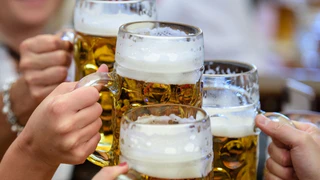 Besucher stoßen auf dem Münchner Oktoberfest mit Bier an. — © Matthias Balk/dpa